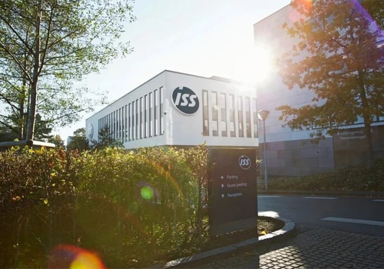 ISS corporate headquarters building with modern white facade, directional signage, and autumn trees in golden sunlight
