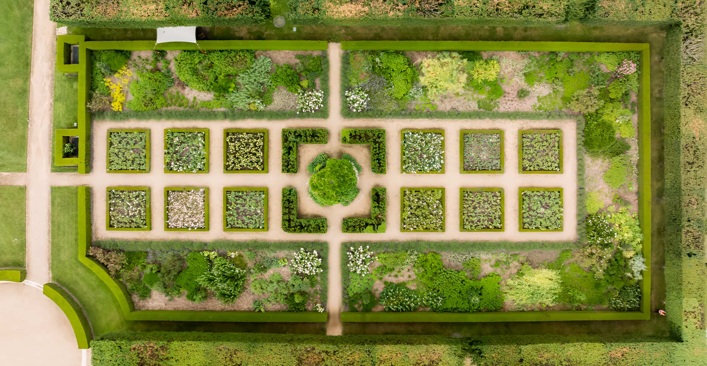 Aerial view of a formal walled garden with symmetrical box-hedged planting beds and gravel paths in a geometric layout