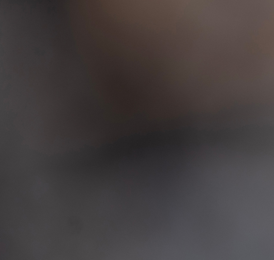 Abstract dark image with minimal visible content, showing a faint shape against a near-black background.
