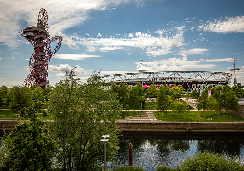 West Ham United Stadium and ArcelorMittal Orbit tower surrounded by lush green landscaped parkland in London
